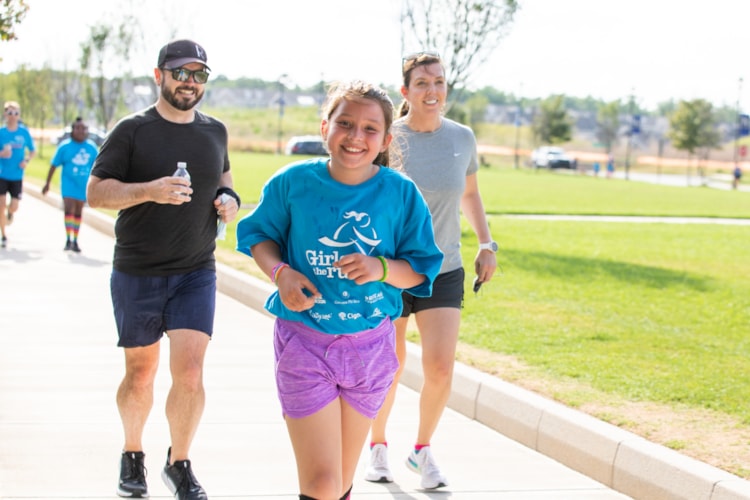 A Girls on the Run participant smiles next to a caregiver as they look down at a journal.